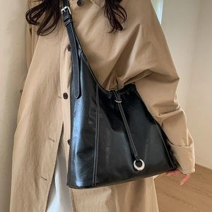 Detail view of black tote bag with white contrast stitching and metal buckle