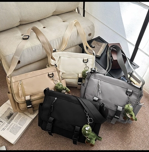 Multiple waterproof nylon messenger bags in four colors with dinosaur plush charms