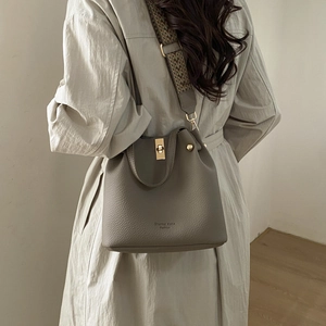 Detail of taupe pebbled leather bucket bag with a chic woven shoulder strap in street style