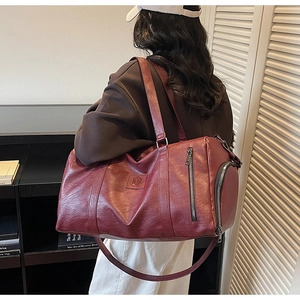 Détail du sac de fitness bordeaux en cuir PU avec logo embossé et compartiment latéral