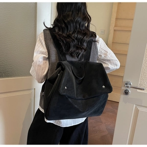 Back view of a large black minimalist backpack with matte finish and flap closure