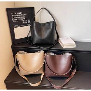 Close-up of three bucket bags in black, beige, and brown with adjustable straps