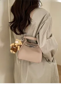 Detail of beige lychee grain bucket bag with cute bear charm and metal buckle
