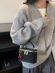 Black woven leather vanity box bag with gold metal handle and cherry charm pendant
