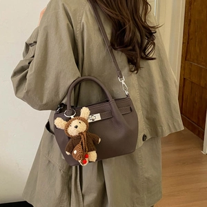 Detail of dark brown pebble leather handbag with silver clasp and cute bear pendant
