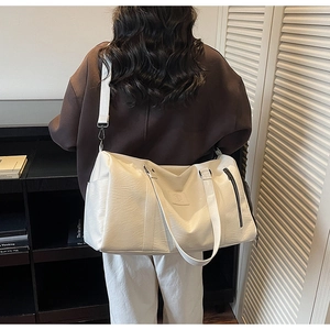 Sac de voyage blanc grande capacité avec bandoulière et texture cuir porté par modèle