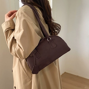 Detailed view of the dark brown matte Boston bag styled with a beige trench coat