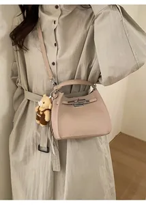 Detail of light pink pebble leather bucket bag with silver buckle and bear charm