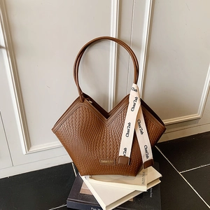 Detail of dark brown woven tote bag featuring a decorative silk ribbon on the handle