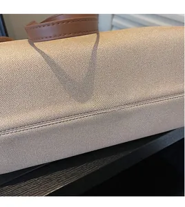 Close-up of beige woven fabric texture and brown leather handles with fine stitching