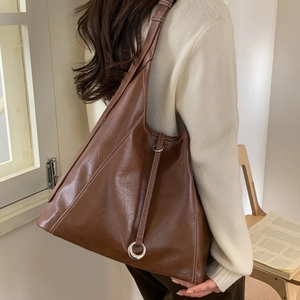 Detail of dark brown tote bag featuring high-contrast white stitching and silver ring