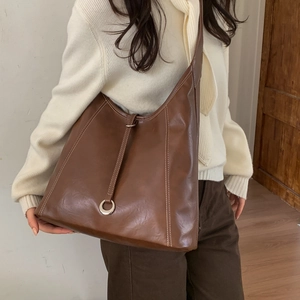 Close-up of brown leather tote bag with contrast stitching and metal ring buckle detail