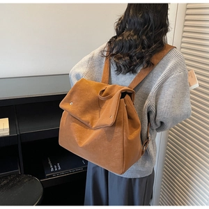 Detail of caramel suede backpack with flap and slender straps on a model in a library