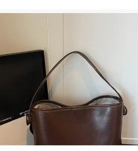Detail view of dark brown leather bucket bag with white contrast stitching and hardware
