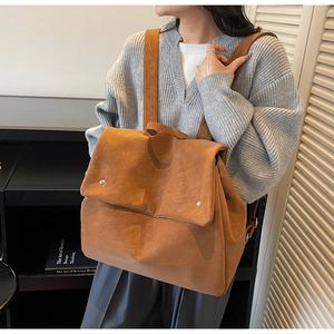 Close-up of brown suede backpack texture with silver rivets and sleek flap closure