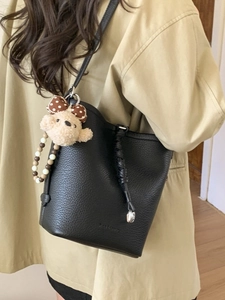 Fashionable black lychee grain leather bucket bag with a cute bear head pendant