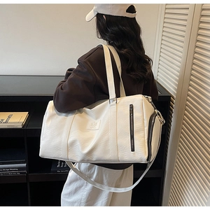 Détail du sac de sport en cuir blanc avec poignées épaisses et poche latérale zippée