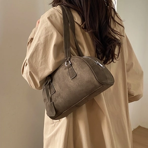 Close-up of matte brown suede Boston bag with long handles and side leather charm