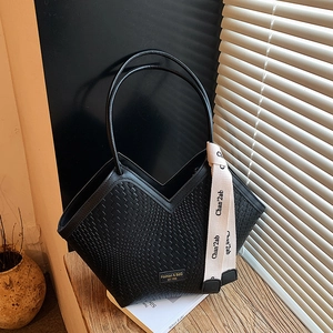 Detail of black woven texture tote bag with elegant silk scarf on the slim handle