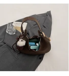 Dettaglio della capienza interna della borsa a mezzaluna marrone con ciondolo di peluche