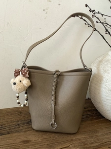 Litchi pattern leather bucket bag in taupe with woven strap and plush puppy pendant
