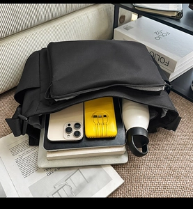 Macro view of a black waterproof shoulder bag showing large capacity for tablets and books