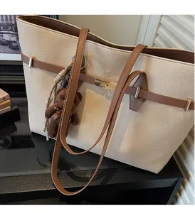 Detail of woven tote bag featuring brown leather trim and cute plush bear charm accessory
