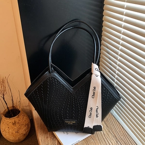 Detail of black woven tote bag with V-shaped opening and decorative silk scarf accessory