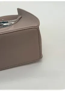 Detail of taupe pebbled leather bucket bag with reinforced wide base and silver hardware