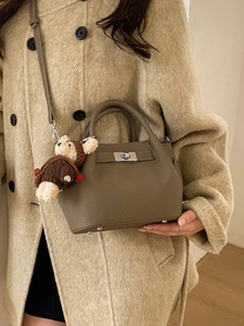 Fashionable brown leather bucket bag for women with cute teddy bear charm and silver lock