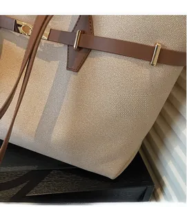 Macro detail of beige textured fabric with brown leather strap and gold metal buckle