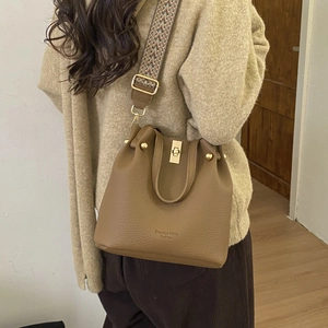 Detailed shot of khaki leather bucket bag featuring a woven geometric shoulder strap