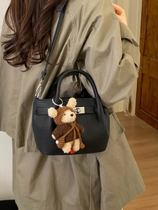 Women's black pebbled leather bucket bag with a cute bear charm and silver twist lock