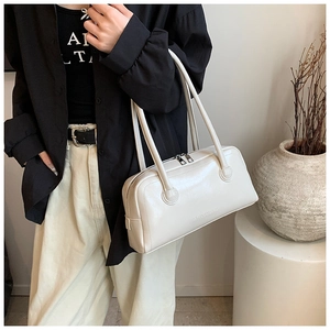 Detail shot of the embossed brand logo on creamy white leather shoulder bag surface