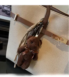 Detail of plush bear charm with love ribbon on large tote bag with metal buckle