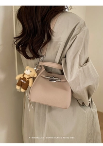 Detail of beige litchi grain bucket bag with silver lock and cute bear pendant charm