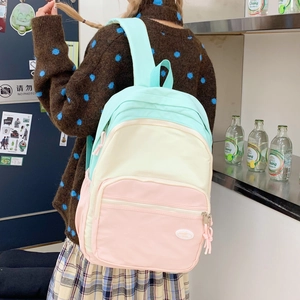 Detailed side view of a tricolor nylon backpack in mint green, beige, and soft pink