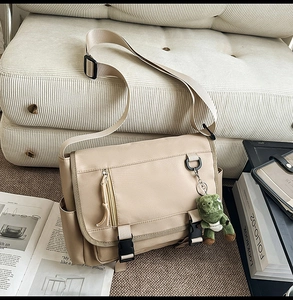 Detail of khaki water-resistant nylon messenger bag with cute dinosaur plush keychain
