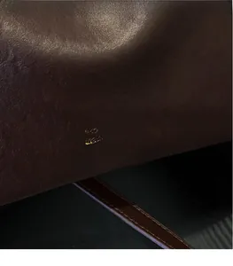 Dettaglio in pelle marrone con elegante logo dorato goffrato su borsa da donna