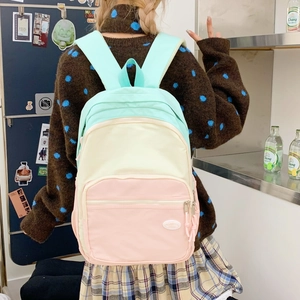 Detailed view of tricolor macaron nylon backpack with multiple zipper pockets on a model