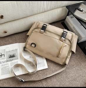 Detail of khaki messenger bag with plastic buckles and adjustable strap in home setting