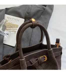 Détails des poignées rondes et boucles dorées sur le sac seau marron foncé