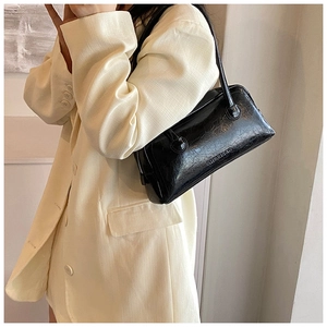 Detailed view of black glossy leather Boston bag showing sleek oil-wax texture and logo