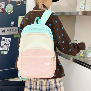 Detailed back view of a multi-color pastel nylon backpack worn by a female model
