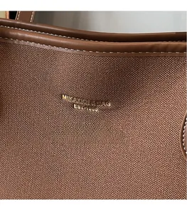 Close-up of brown pebbled leather texture with white stitching and gold logo details