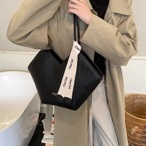 Detail of black woven tote bag with V-shaped opening and beige branded strap handles