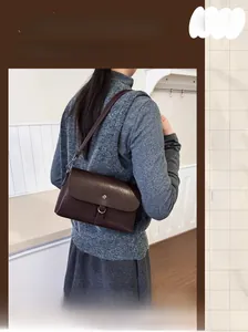 Detail view of a vintage dark brown shoulder bag with a metal buckle and flap design