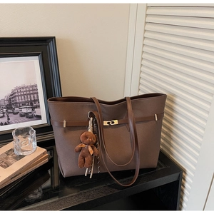 Detail of vintage brown tote bag with metal lock and cute teddy bear plush charm