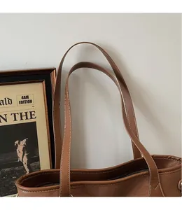 Detail of vintage brown tote bag featuring long leather shoulder straps and white stitching