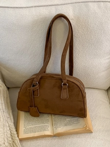 Vintage brown suede Boston bag with silver zipper on a book, retro shoulder bag style